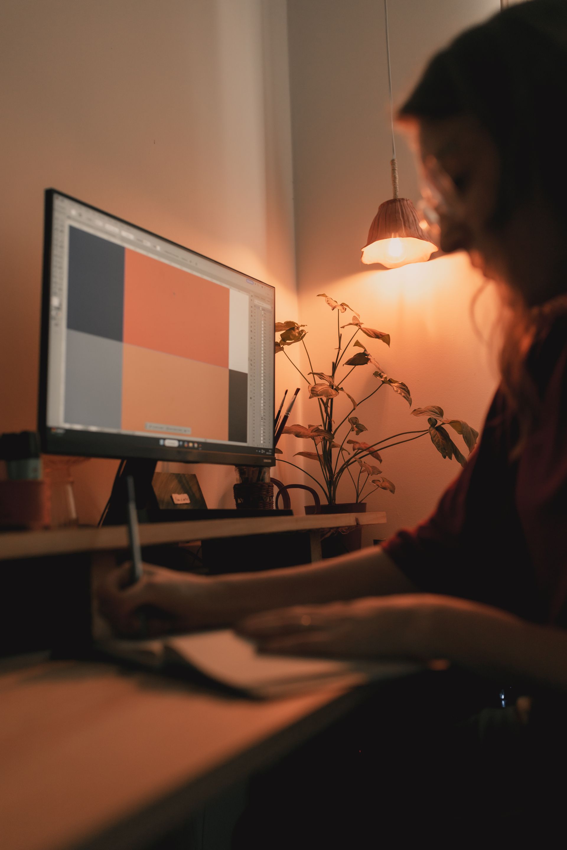 A designer working at a creative studio desk, sketching on a large monitor with art tools around, warmly lit